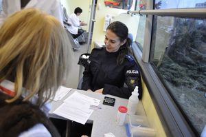 Na zdjęciu widoczne dwie kobiety z czego jedna w policyjnym mundurze w trakcie rejestracji przed honorowym oddaniem krwi.