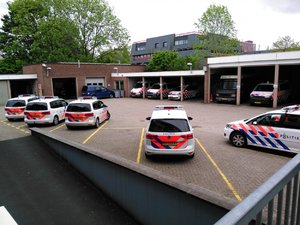 Zdjęcie przedstawia holenderskie radiowozy zaparkowane na parkingu przy komendzie