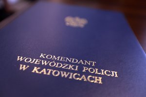 Zdjęcie przedstawia fragment teczki z napisem &quot;Komenda Wojewódzka Policji w Katowicach&quot;, w której znajdują się rozkazy personalne