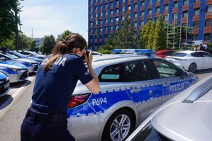 Policjantka fotografuje nowe radiowozy.