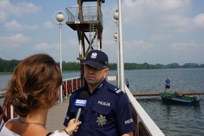 Policjant wypowiada się dla dziennikarzy podczas briefingu nad jeziorem Pogoria III w Dąbrowie Górniczej