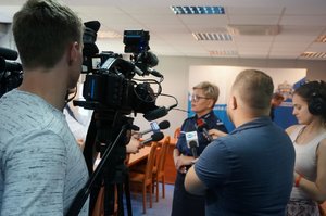 Podinspektor Aleksandra Nowara podczas udzielania wypowiedzi dla mediów w otoczeniu przedstawicieli telewizji, radia i prasy