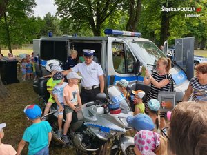 umundurowany policjant pozuje do wspólnego zdjęcia z dziećmi siedzącymi na motocyklu