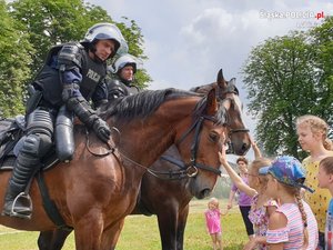 policjanci na koniach oraz dzieci głaszczące zwierzęta