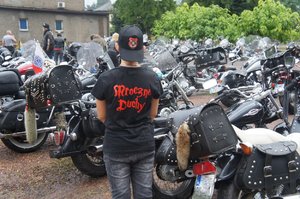 motocyklista w koszulce z napisem mroczne duchy na tle motocykli