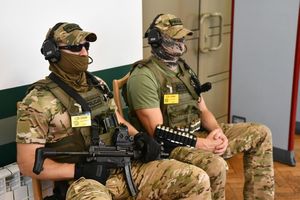 Dwaj uzbrojeni kontrterroryści siedzący na ławce w sali rozpraw