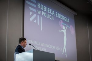 Zdjęcie kolorowe. Aula Komendy Wojewódzkiej Policji w Katowicach, do uczestniczek zwraca się jeden z prelegentów