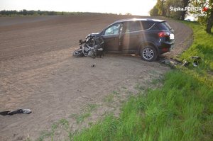 Zdjęcie z wypadku motocyklisty, który zderzył się z samochodem osobowym. Rozbite pojazdy na polu.