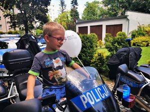 Chłopiec siedzi na motocyklu policyjnym.