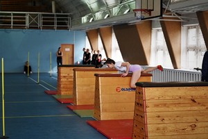 zdjęcie przedstawia osobę pokonującą tor przeszkód- przeskakującą nad skrzynią gimnastyczną