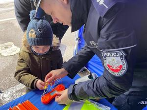 Na zdjęciu policjant z drogówki gra z dzieckiem w grę sprawdzającą koordynację wzrokowo - ruchową.