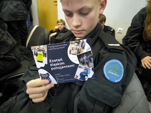 Zdjęcie. Uczeń czyta ulotkę poświęcona rekrutacji do Policji