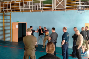 Na zdjęciu grupa policjantów ćwiczy z bronią służbową podczas szkolenia.