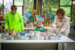 Na zdjęciu dwójka dzieci i kobieta podczas malowania farbami.
