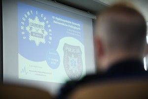 na zdjęciu wyświetlony na tablicy slajd, 9 Ogólnopolskie Zawody Ratowników Policyjnych z Kwalifikowanej Pierwszej Pomocy. Przed częściowa sylwetka mężczyzny