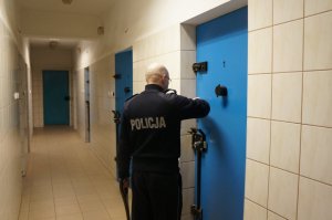 Policjant zamykający celę w izbie zatrzymań
