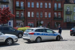Umundurowany policjant przy radiowozie stojący na Placu Kolei Warszawsko - Wiedeńskiej