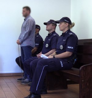 Zdjęcie kolorowe. Podejrzany na ławie oskarżonych w sądzie oraz 3 policjantów