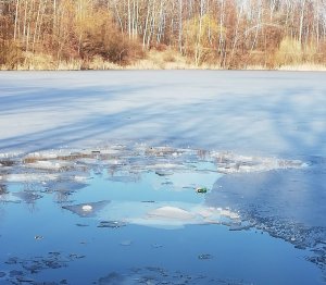 zdjęcie przedstawia popękany lód na zbiorniku wodnym