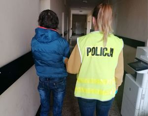 Policjantka doprowadza korytarzem zatrzymaną