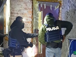 Nieumundurowani policjanci stoją przy otwartych drzwiach