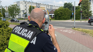 Na zdjęciu policjant wykonujący pomiary specjalnym teodolitem.