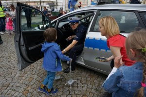 chłopiec podaje rękę policjantce siedzącej w radiowozie