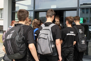 Młodzież w koszulkach z napisem klasa policyjna wchodzi wejściem głównym do komendy.