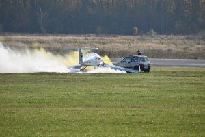 zdjęcie kolorowe: na płycie lotniska samolot sportowy i samochód osobowy, który zderzył się z samolotem
