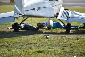 zdjęcie kolorowe: dwie osoby ranne leżące pod samolotem na płycie lotniska