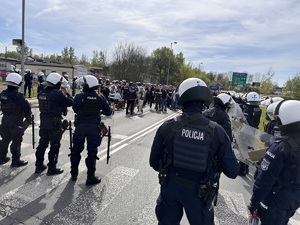 zdjęcie kolorowe: policjanci nadzorujący przemarsz kibiców na stadion