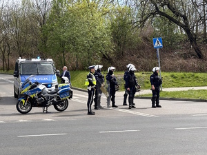 zdjęcie kolorowe: policjanci zabezpieczający drogę przemarszu kibiców