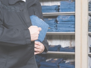 zdjęcie przedstawia mężczyznę chowającego spodnie pod kurtkę w sklepie.
