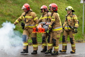 zdjęcie przedstawia strażaków niosących poszkodowanego