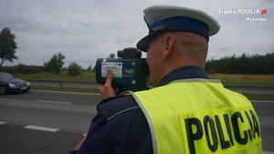 Na zdjęciu policjant stojący z miernikiem prędkości