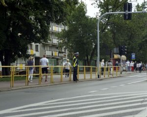 Fotografia kolorowa. Na zdjęciu widoczny policjant w rejonie skrzyżowania.