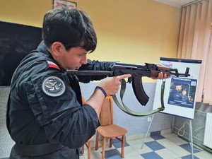 Zdjęcie przedstawia: ucznia klasy mundurowej z bronią.
