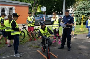 Kolejni uczniowi pokonują specjalny tor jazdy na rowerze pod nadzorem policjanta z raciborskiej drogówki