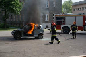 Strażak gasi płonący samochód