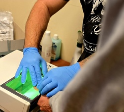 na zdjęciu technik pobiera odciski palców