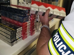 zdjęcie przedstawia policjanta trzymającego przechwycone paczki papierosów