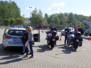 Na zdjęciu osoby zainteresowane policyjnym radiowozem i motorami.