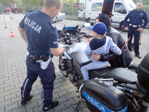 Policjant WRD, motor oraz małe dziecko, które siedzi na motorze.
