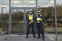 Zdjęcie przedstawia dwóch, umundurowanych policjantów z Wydziału Ruchu Drogowego na tle budynku komendy.