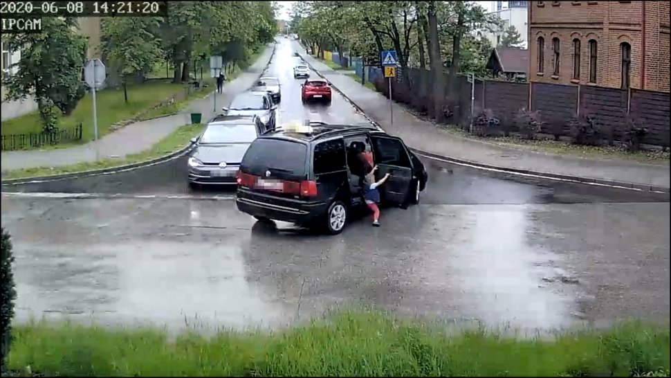 Na zdjęciu widać skrzyżowanie, na którym z jednego z widocznych samochodów, przez tylne drzwi wypada dziecko