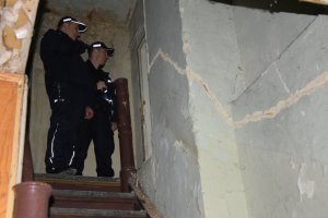 Na fotografii widać klatkę schodową, na której stoją dwaj policjanci