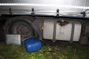 Miejsce włamania. Na zdjęciu widoczny bak ciężarówki o wyłamanym korkiem wlewu. Obok leżą porzucone dwa plastikowe pojemniki i rurka do spuszczania paliwa.