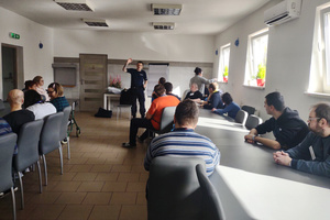 Zdjęcie: Warsztaty Terapii Zajęciowej w Łazach. Na zdjęciu widoczny jest umundurowany policjant, który prowadzi spotkanie z uczestnikami warsztatu.