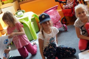 Troje dzieci, trzy dziewczynki, w środku dziewczynka w policyjnej czapce
