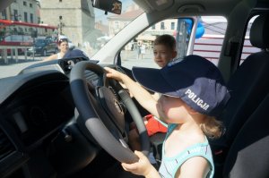 dziecko w policyjnej czapce za kierownicą radiowozu